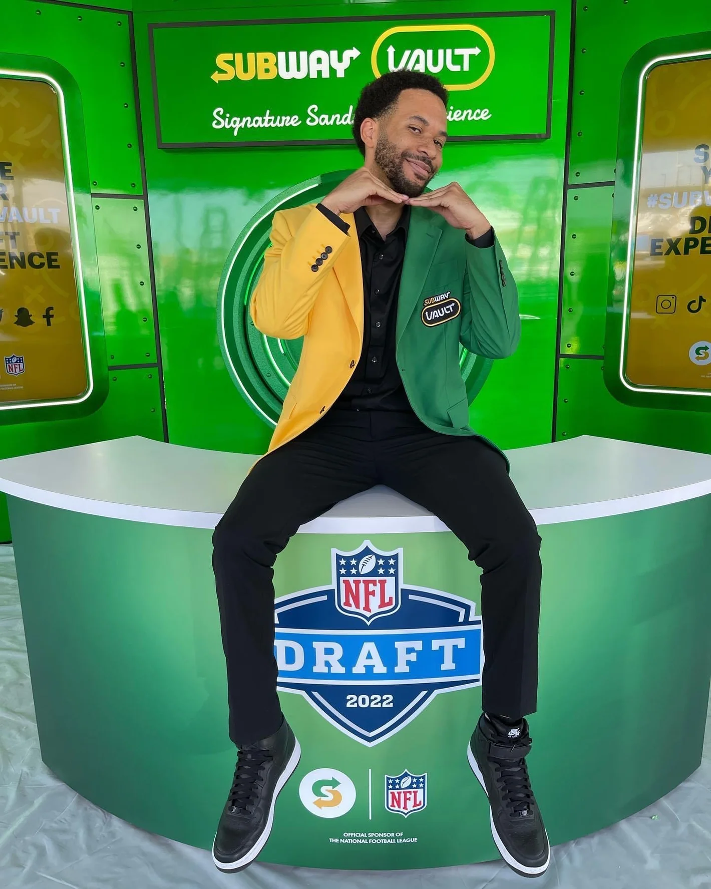 Photo of a man wearing a green a yellow blazer branded with Subway food chain