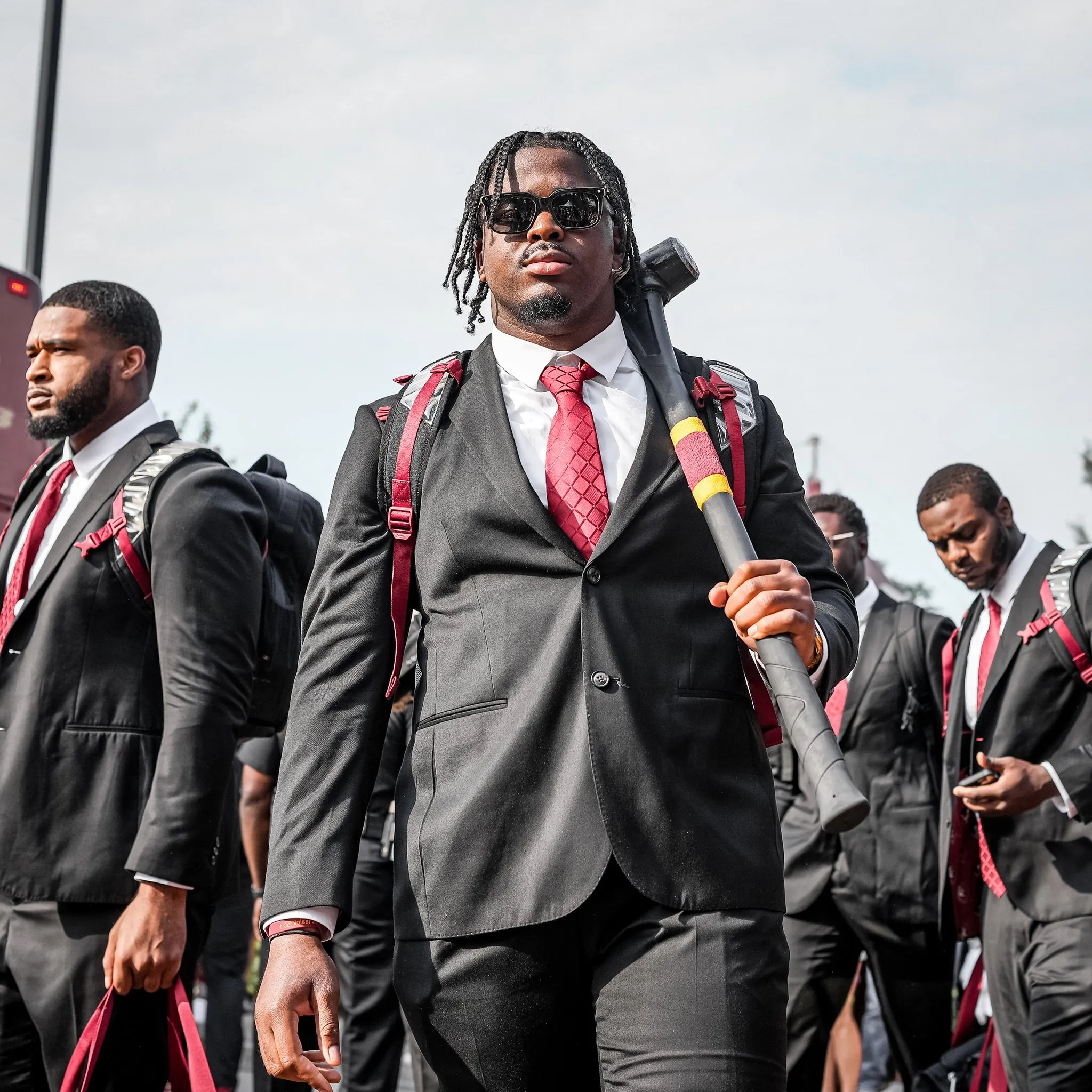 Group of sportsmen walking in a parade with grey suits.