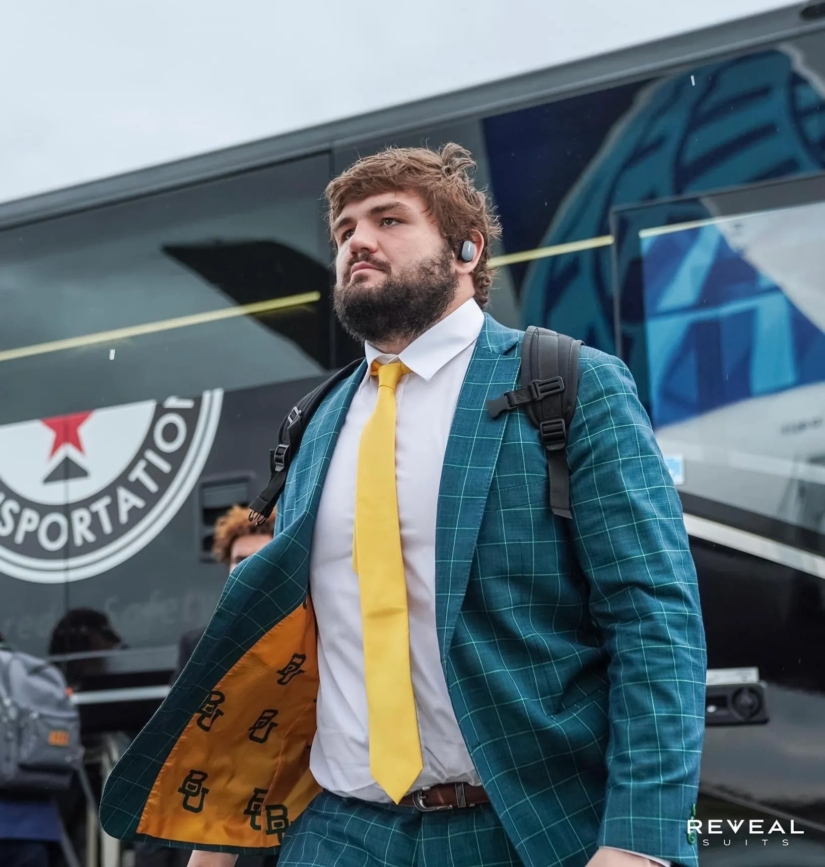 Sportsman wearing a green suit walking out a bus.