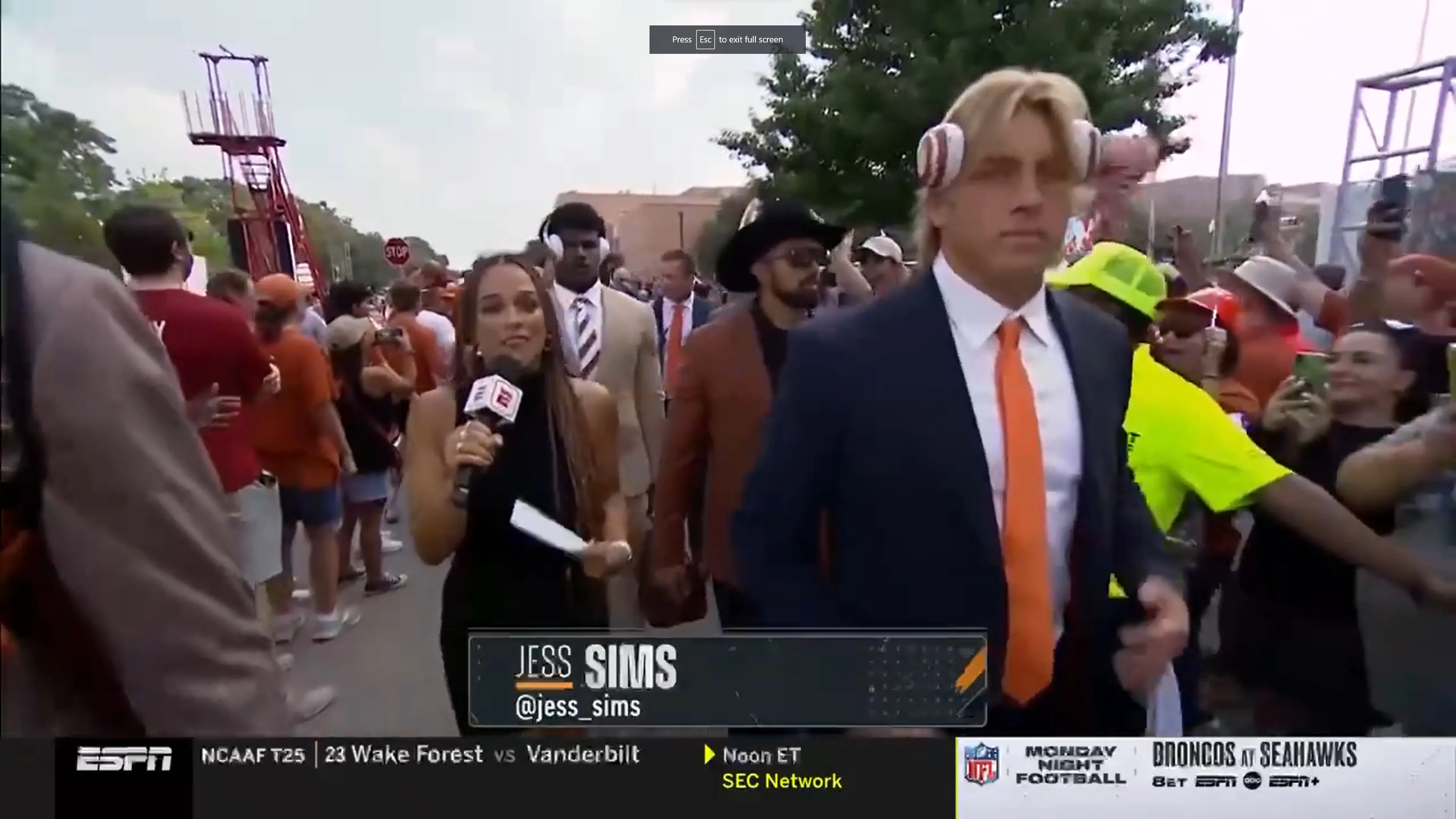 Reporter interviewing athletes while they walk towards the stadium before the game.